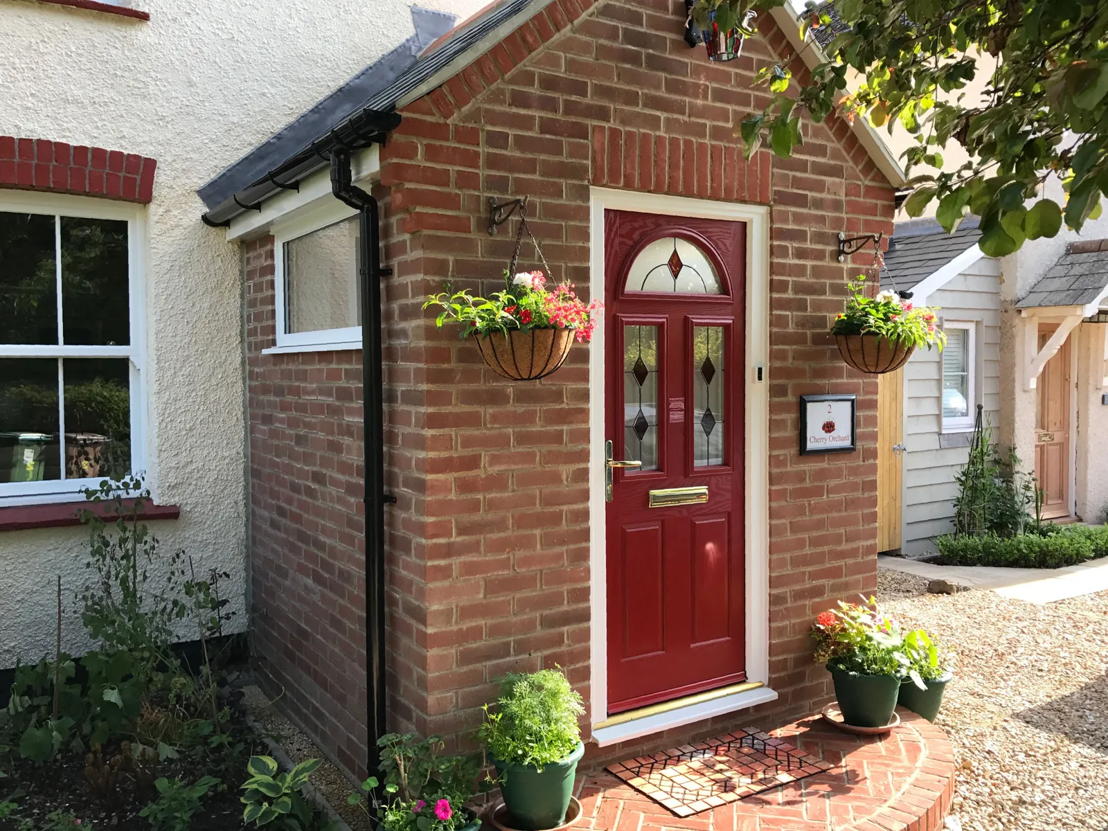 A red front door with leaded glass and a hanging basket, fitted by Hanney Glazed