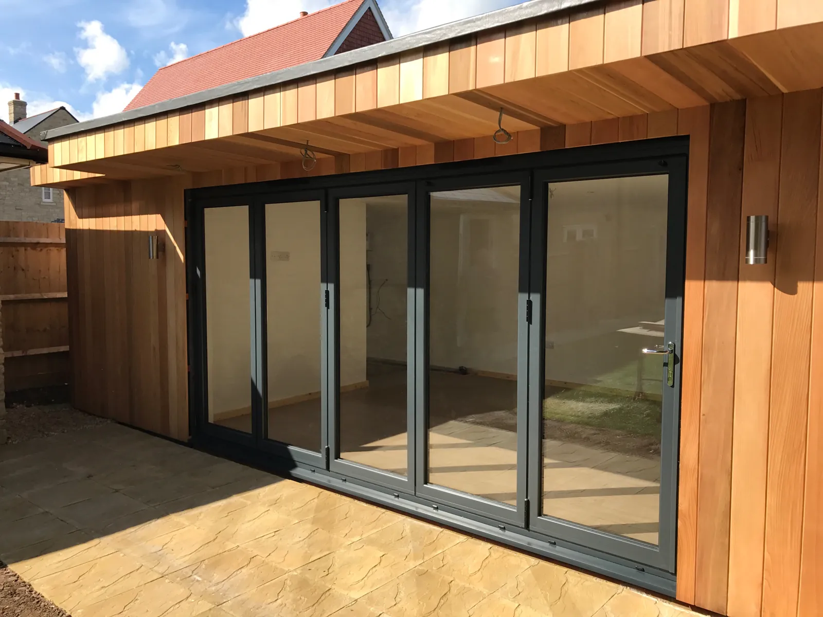 A cedar-clad garden office with grey aluminium bi-folding doors, built by Hanney Glazed