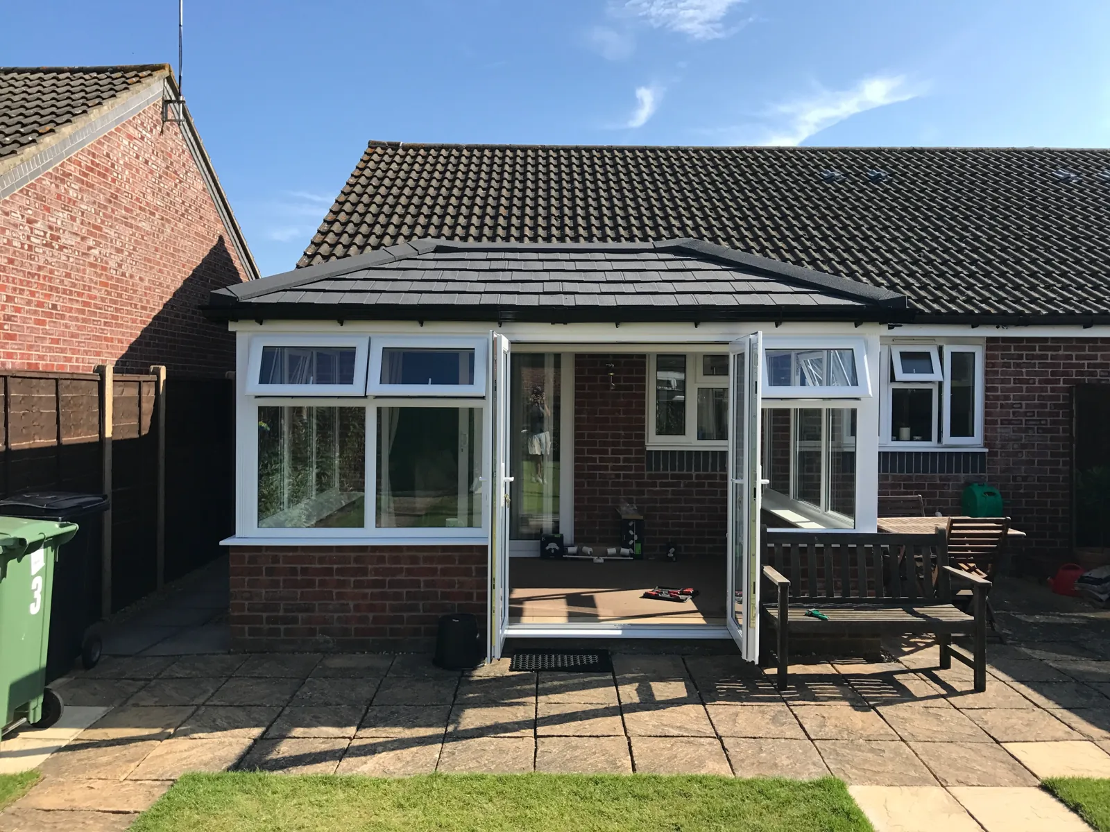 A conservatory on a bungalow with a new grey tiled roof