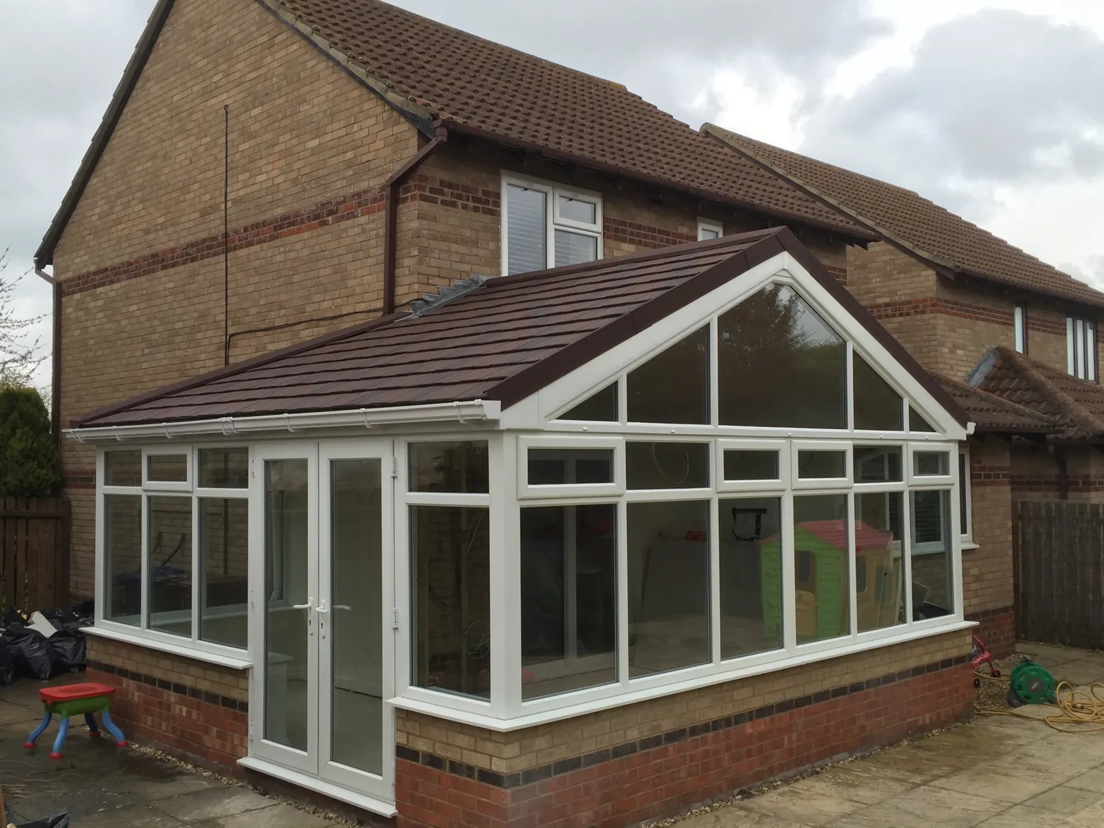 A gable-ended conservatory with a new brown tiled roof